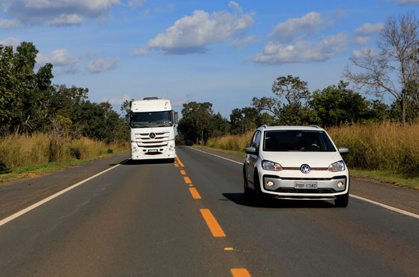 Volkswagen e-UP driving on the road with a truck behind